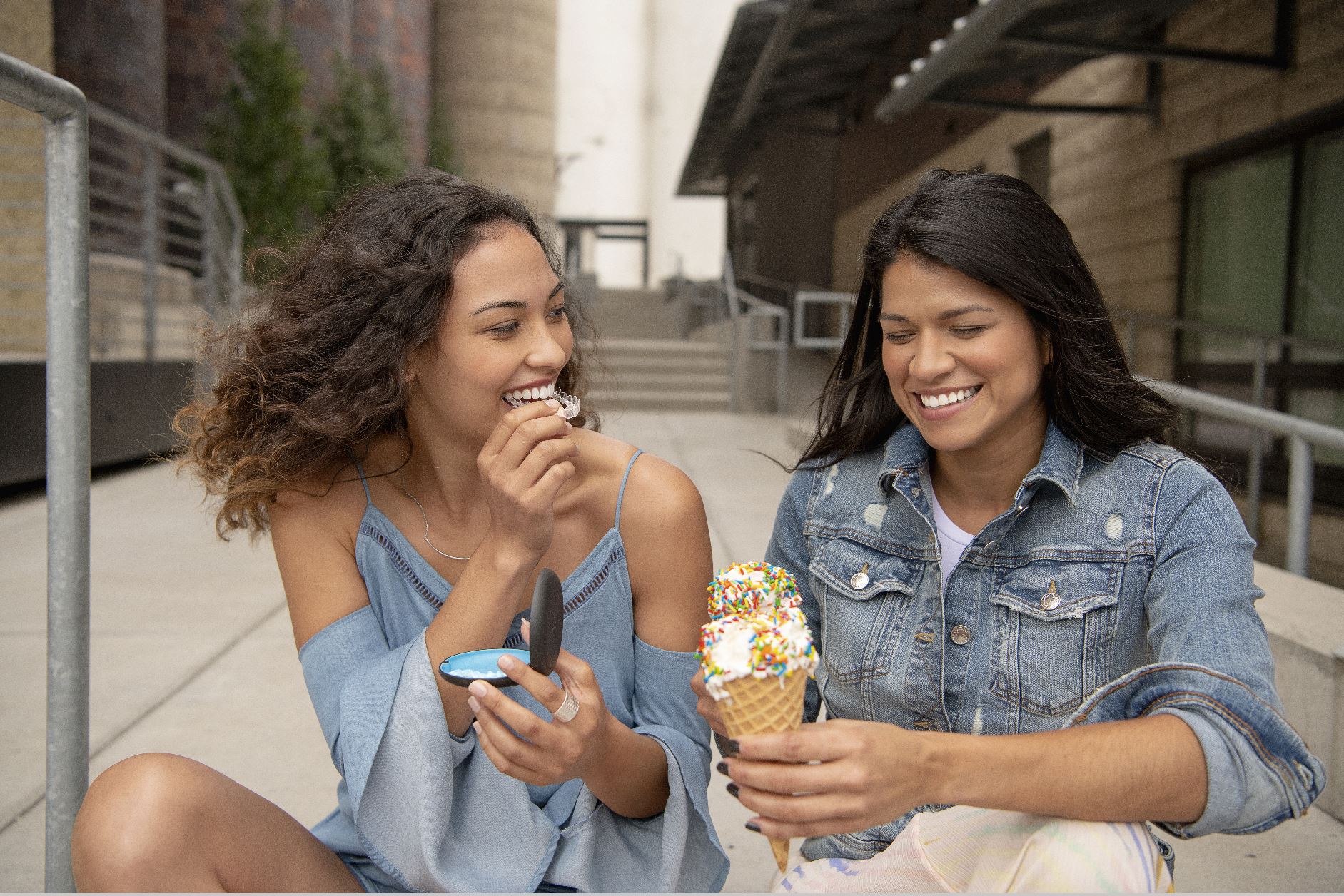 Two young women laughing, one removing her Invisalign Teen aligner for ice cream